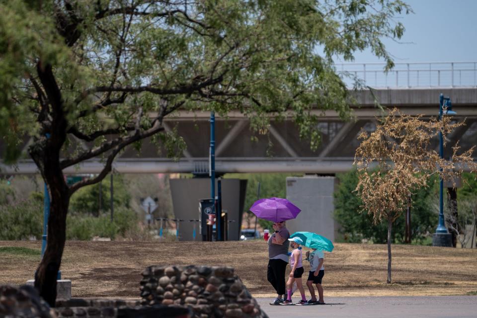 People walk along Tempe Town Lake as hot temperatures continue in Tempe on July 13, 2023.