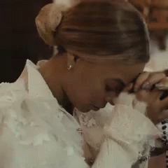 Beyoncé bowing her head and clasping her hands together