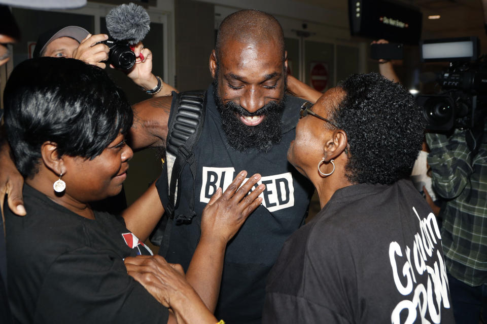 Wendell Brown hugs relatives after his arrival at the Detroit Metropolitan Airport, Wednesday, Sept. 25, 2019, in Romulus, Mich. Brown returned from China where he was imprisoned for his involvement in a bar fight. Brown, a native of Detroit had been teaching English and American football in southwest China when he was arrested in September 2016 and charged with intentional assault. (AP Photo/Carlos Osorio)