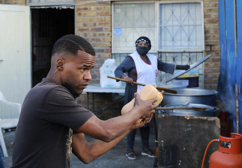 In this May 2, 2020, photo, a gang member delivers butternut squash to a soup kitchen in the Manenberg neighborhood in Cape Town, South Africa. Members of rival street gangs have been recruited to distribute food to struggling families during the coronavirus lockdown. (AP Photo/Nardus Engelbrecht)