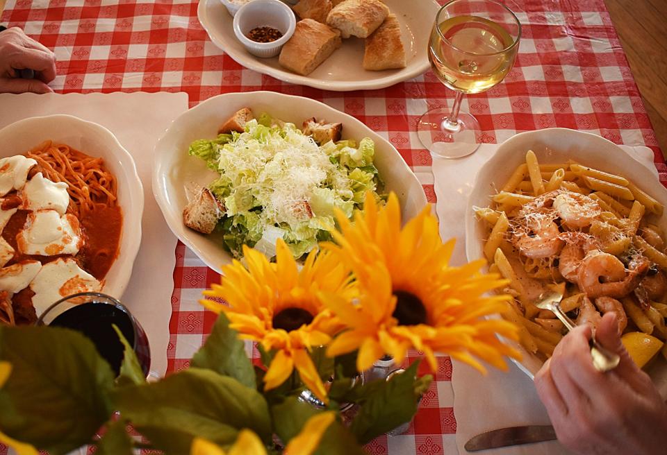 DIners enjoy chicken parmesan and shrimp scampi along with a Ceasar salad and an order of house-baked bread at The Italian Kitchen at The Don Carlos Club in Fall River.