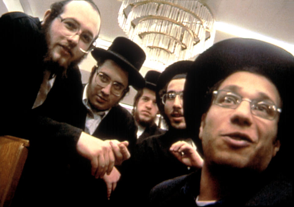 A group of Jewish men huddle around a camera