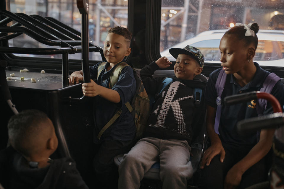 Damien Salinas, 5 years old, center right, rides the bus on his way to school on Thursday, Sept. 7, 2023, in New York. Damien attends his first day of school in New York City after his family emigrated from Ecuador in June. Damien and her family have been living in a room at the historic Roosevelt Hotel, converted into a city-run shelter for newly arrived migrant families hoping to find work, a new home and a better life for their children. (AP Photo/Andres Kudacki)