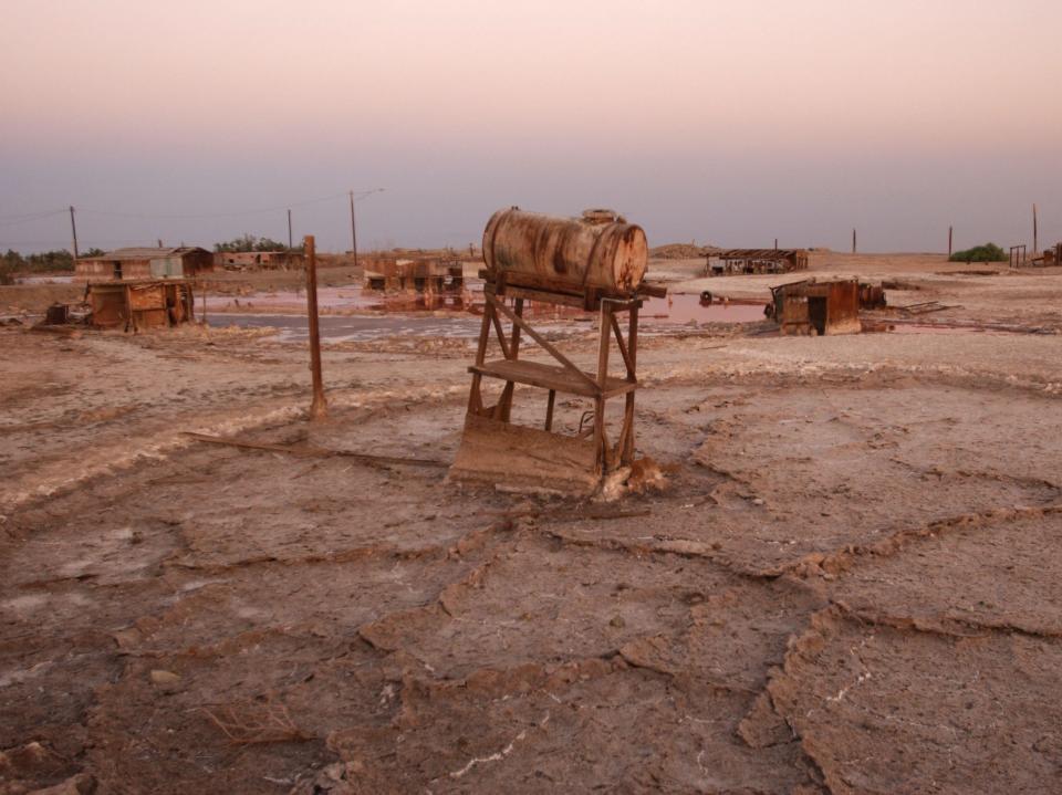 A water tower leans in the briny mud where the remains of flooded houses and trailers stand at Bombay Beach in 2003.