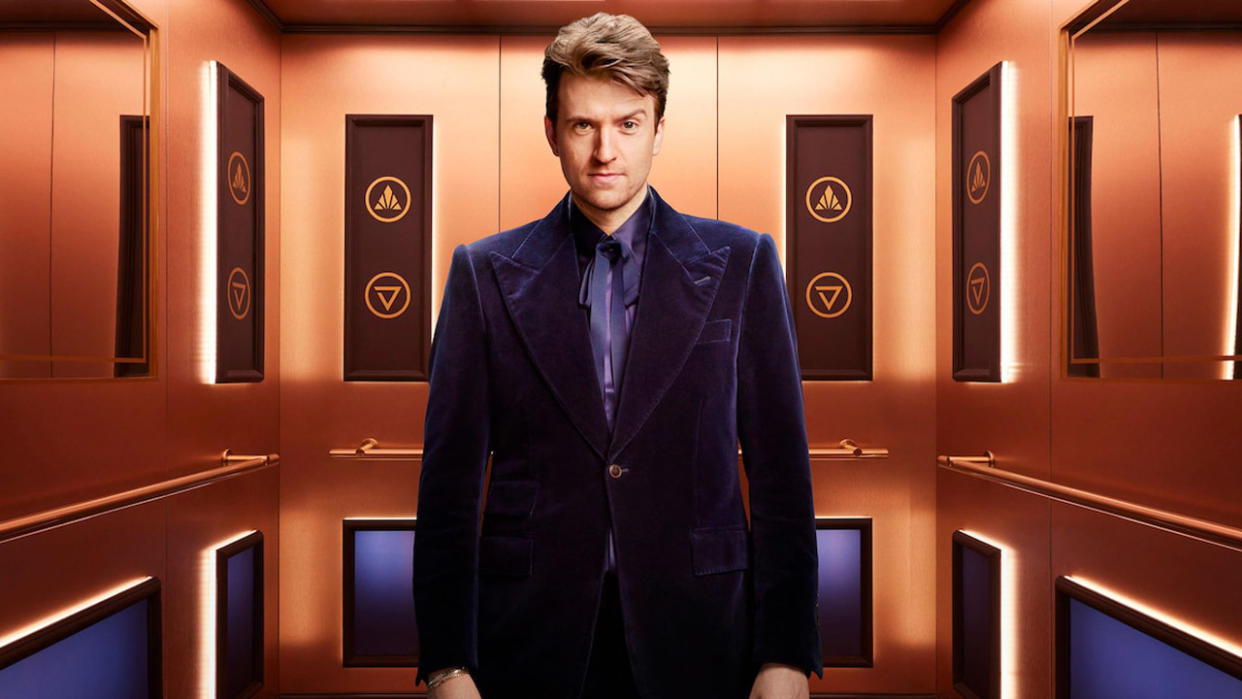  Greg James stands in the elevator of Rise and Fall 