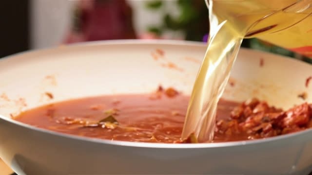 Adding chicken stock to pan of tomato sauce