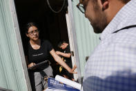 Evelyn Lara, de 19 años, con su hermano Iker, de 7, abre la puerta a Ricky Hurtado, candidato demócrata a la Cámara estatal de Representantes de Carolina del Norte, que hace campaña en un parque de casas rodantes de mayoría latina en Burlington, Carolina del Norte, el domingo 8 de marzo de 2020. (AP Foto/Jacquelyn Martin)