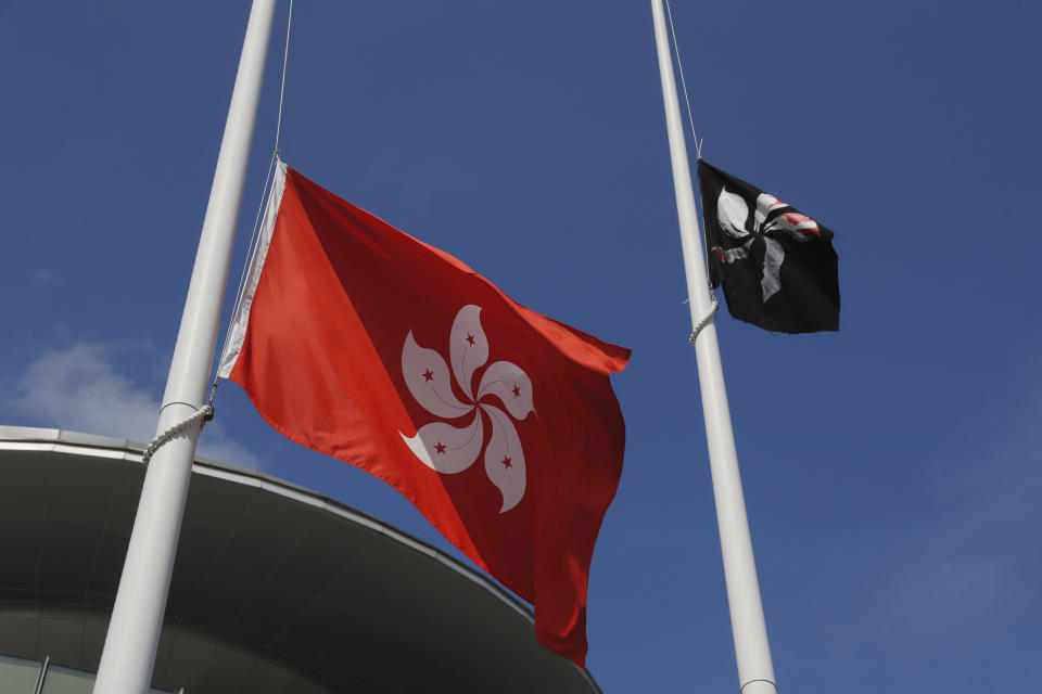 A black Hong Kong flag flies as protesters replaced with the Chinese flag that is normally set up next to a Hong Kong flag, left, in Hong Kong on Monday, July 1, 2019. The Hong Kong government marked the 22nd anniversary of the former British colony's return to China on Monday, as police faced off with protesters outside the venue. (AP Photo/Kin Cheung)