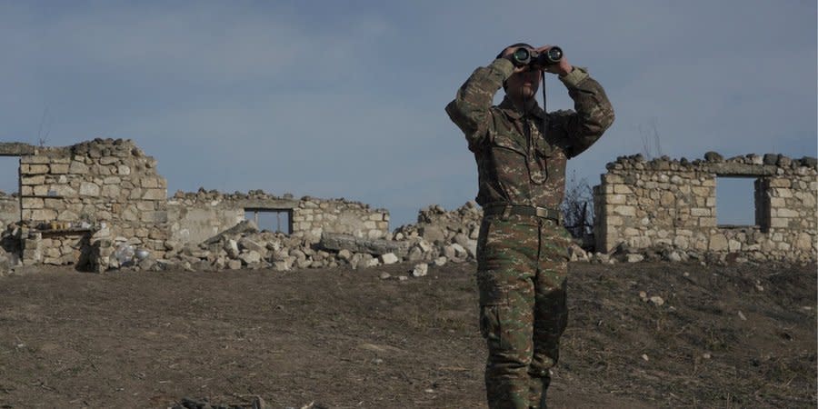 An Armenian soldier looks through binoculars at a combat position near the village of Tagavard in Karabakh, January 2021