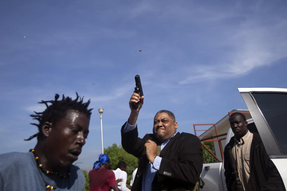 Opposition Senator Ralph Fethiere fires his gun outside Parliament as he arrives for a ceremony to ratify Fritz William Michel's nomination as prime minister in Port-au-Prince, Haiti, Sept. 23, 2019. Opposition members confronted ruling-party senators, and Fethiere pulled a pistol when protesters rushed at him and members of his entourage. The image was part of a series of photographs by Associated Press photographers which was named a finalist for the 2020 Pulitzer Prize for Breaking News Photography. (AP Photo/Dieu Nalio Chery)