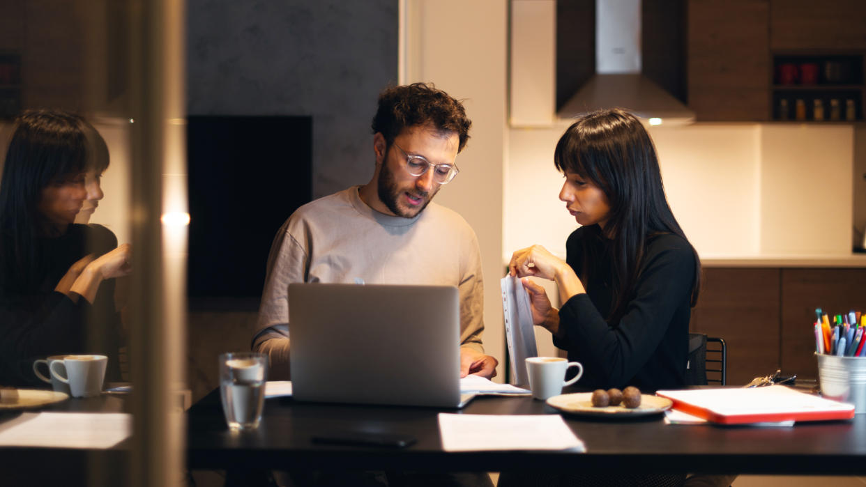 Young couple is sitting at the table with laptop and paying bills online.