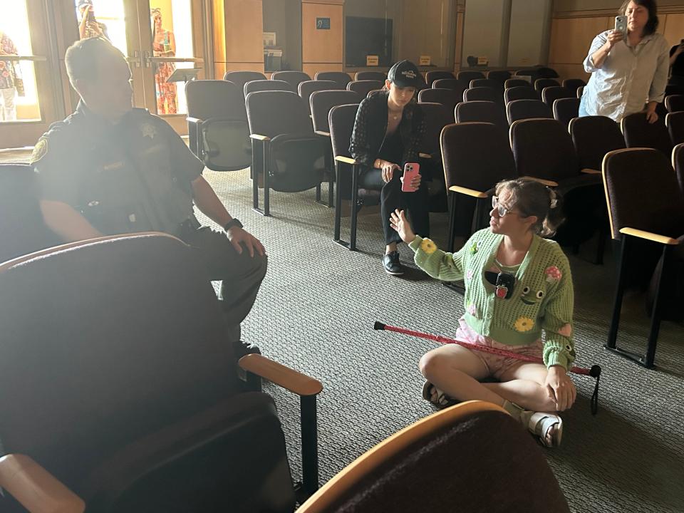 Jenny Nowain sits on the floor of the Shasta County Board of Supervisors chambers Tuesday, July 23, 2024. The meeting was shut down due to disruptions, but Nowain refused to leave the chambers until Supervisor Patrick Jones apologized to her.