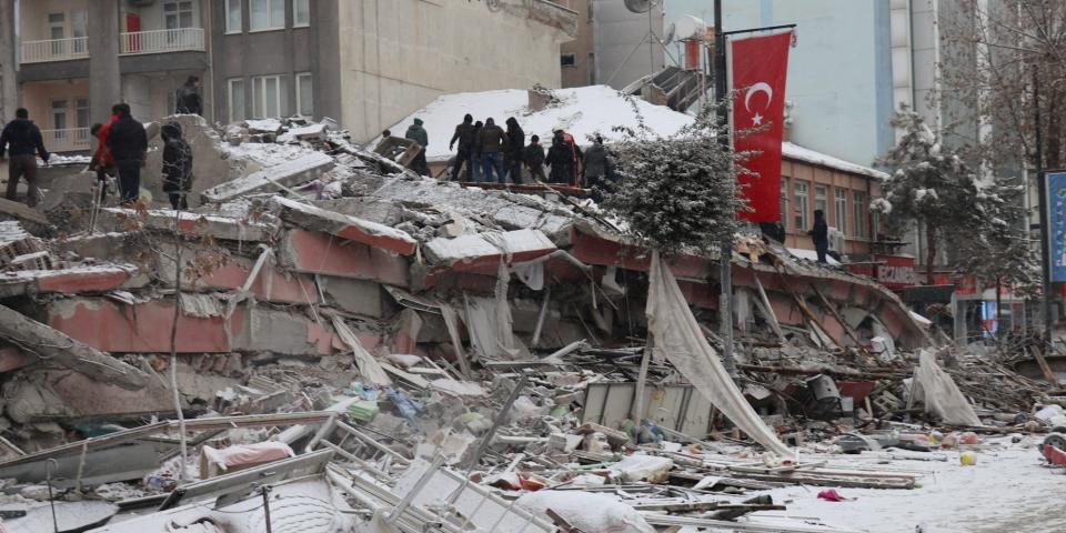 Rescuers carry a person from the ruins of a collapsed building, lightly covered in snow, in Malatya, Turkey, following the earthquake on February 6, 2023