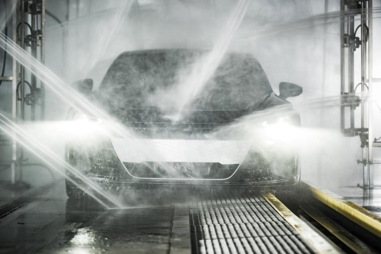 Modern Grand Touring Car Inside Powerful Touchless Car Wash. Front View. Automotive Technologies Theme.