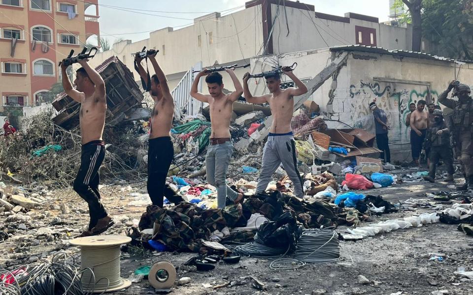 Palestinian men carry weapons as they are taken for questioning by the IDF