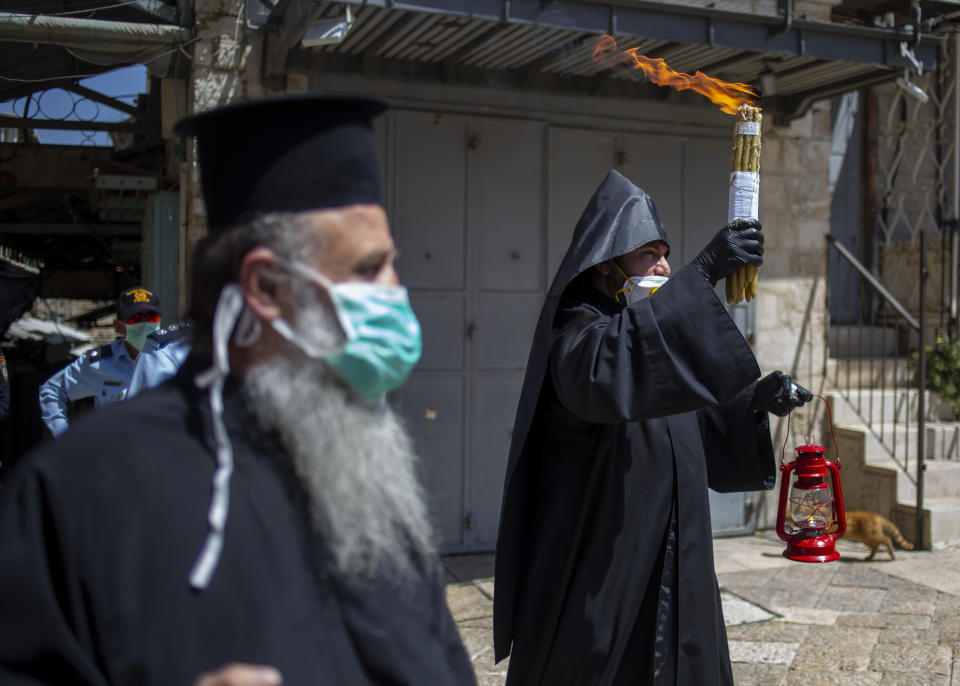 An Orthodox clergyman holds holy fire to transfer to predominantly Orthodox countries from the Church of the Holy Sepulchre, traditionally believed by many Christians to be the site of the crucifixion and burial of Jesus Christ, in Jerusalem's old city the traditional Holy Fire ceremony was called off amid coronavirus, Saturday, April 18, 2020. A few clergymen on Saturday marked the Holy Fire ceremony as the coronavirus pandemic prevented thousands of Orthodox Christians from participating in one of their most ancient and mysterious rituals at the Jerusalem church marking the site of Jesus' tomb.(AP Photo/Ariel Schalit)