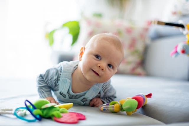 Cute baby boy, playing with toys in a sunny living room