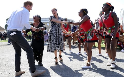 The Duke and Duchess of Sussex dance as they visit a Justice Desk initiative in Nyanga township - Credit: Chris Jackson