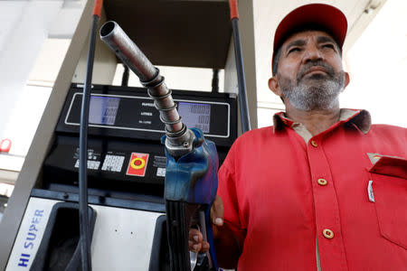An employee of Total Parco gas station holding a nozzle as he prepares to fill fuel in a vehicle in Karachi, Pakistan April 2, 2019. REUTERS/Akhtar Soomro/Files