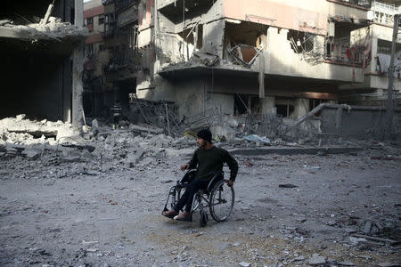 A man in a wheelchair is seen at a damaged site after an airstrike in the besieged town of Douma, Eastern Ghouta, Damascus, Syria February 9, 2018. REUTERS/Bassam Khabieh