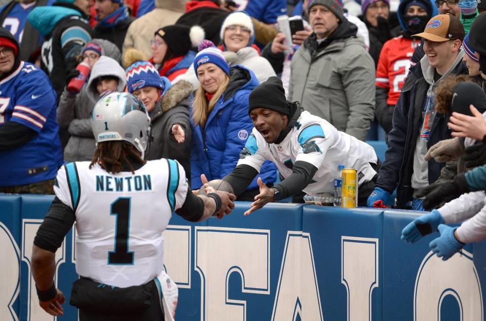 Carolina Panthers quarterback Cam Newton, left, hands a football to a fan after the team scored on a two-point conversion against the Buffalo Bills during second quarter action at Highmark Stadium in Orchard Park, NY on Sunday, December 19, 2021.