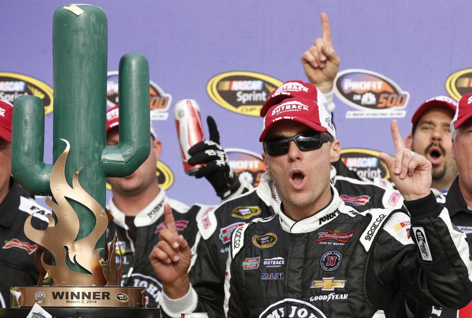 Kevin Harvick poses for photographers with the winner's trophy after his victory in the NASCAR Sprint Cup Series auto race Sunday, March 2, 2014, in Avondale, Ariz. (AP Photo/Ross D. Franklin)