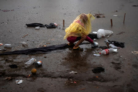 A migrant girl, part of a caravan of thousands from Central America trying to reach the United States, collects plastic cups floating in rainwater at a shelter in Tijuana, Mexico November 29, 2018. REUTERS/Adrees Latif