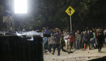 Student protesters throw stones to riot police during a protest outside the parliament in Jakarta, Indonesia Tuesday, Sept. 24, 2019. Police fired tear gas and water cannons Tuesday to disperse thousands of rock-throwing students protesting a new law that they said has crippled Indonesia's anti-corruption agency.(AP Photo/Achmad Ibrahim)