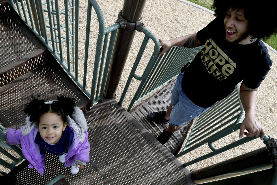 Michael Diaz-Rivera plays with his 2-year-old daughter Aria at a Denver park on Friday, April 23, 2021. Diaz-Rivera was pulled over in Colorado Springs, Colo. in 2006, and officers found two bags of marijuana in his car. After he was convicted of felony drug possession, he struggled to find housing, ran into hurdles while applying for federal student aid and was denied jobs. Now an elementary school teacher, he sees his future in a pot delivery business made possible by Colorado's marijuana social equity program, which is aimed at correcting past wrongs from the war on drugs. Diaz-Rivera says he hopes his business will allow him to pass on to his children generational wealth that he did not have growing up. (AP Photo/Thomas Peipert)