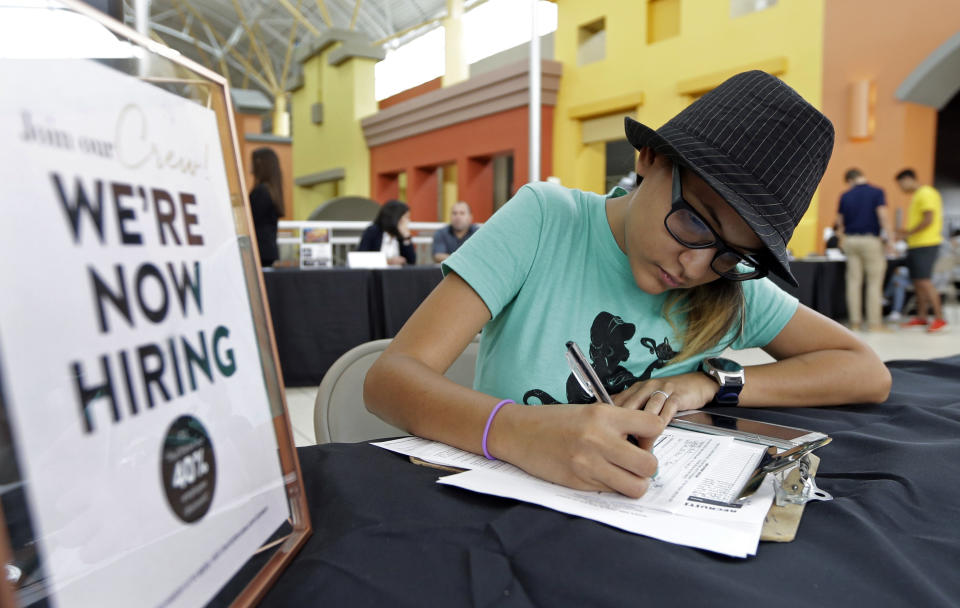 FILE - In this Oct. 4, 2017 file photo, job seeker Alejandra Bastidas fills out an application at a job fair in Sweetwater, Fla.  U.S. workers’ wages and benefits grew 2.6 percent last year, the fastest 12-month pace since the spring of 2015. The 12-month gain in wages and benefits came despite a slight slowdown at the end of last year with wages and benefits rising 0.6 percent in the fourth quarter, a tiny dip from a 0.7 percent gain in the third quarter. Still, the 12-month gain was an improvement from a 2.2 percent gain for the 12 months ending in December 2016. (AP Photo/Alan Diaz, File)