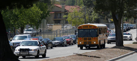 Police cars escort students in a bus after a shooting at North Park Elementary School, to be reunited with their parents in San Bernadino, California, U.S. April 10, 2017. REUTERS/Mario Anzuoni