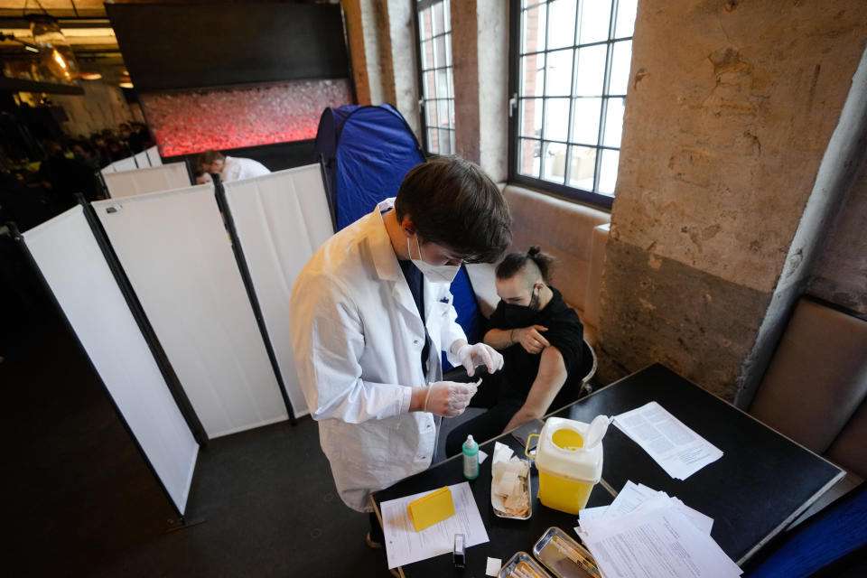 A doctor takes a plaster after he injects vaccination against the coronavirus and the COVID-19 disease to a man inside the Sage Beach Bar and Restaurant in Berlin, Germany, Monday, Jan. 3, 2022. The Clubcommission Berlin, an association that protects and supports the Berlin club culture, start a vaccination campaign which take place in several clubs bars and restaurants in the German capital. (AP Photo/Markus Schreiber)