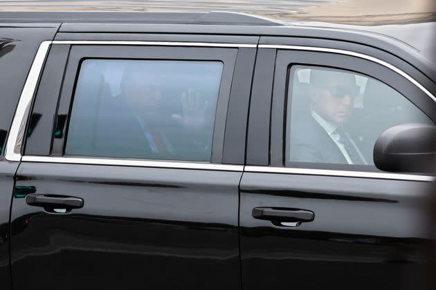 Trump waves from the back seat of his vehicle as he departs the courthouse after being arraigned.