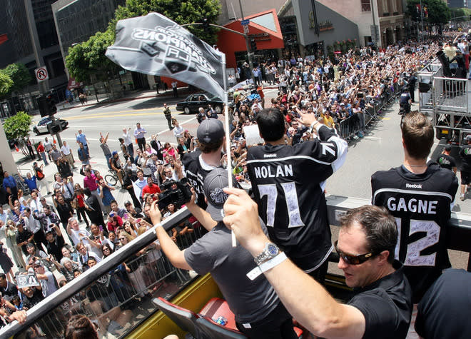 LOS ANGELES, CA - JUNE 14: Los Angeles player development coach Nelson Emerson waves a flag as Jordan Nolan #71 and Simon Gagne #12 of the Los Angeles look on from the bus during the Los Angeles Kings Stanley Cup Victory Parade on June 14, 2012 in Los Angeles, California. (Photo by Victor Decolongon/Getty Images)