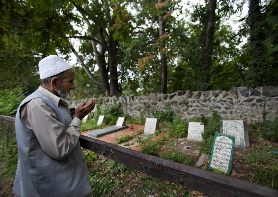 FILE - In this Sept. 5, 2012 file photo, a Kashmiri Muslim prays near an unmarked grave, right foreground, that reads, "unidentified fifteen year old boy shot and killed by Border Security Force soldiers on 5th September 2003," inside a martyrs graveyard in Srinagar, Indian controlled Kashmir. A prominent rights group in Indian-controlled Kashmir is advocating United Nations to establish a commission of inquiry to probe endemic use of torture by government forces who have faced decades long anti-India uprising in the disputed region. (AP Photo/ Dar Yasin, File)