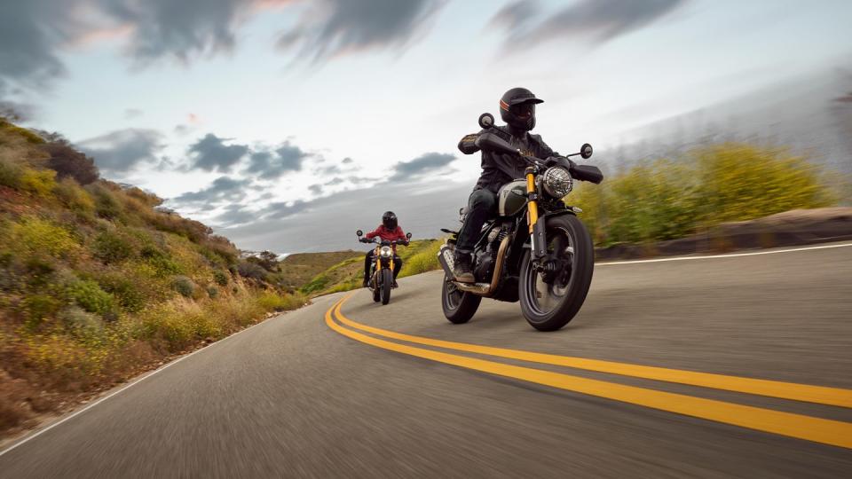 a couple of people ride motorcycles down a road