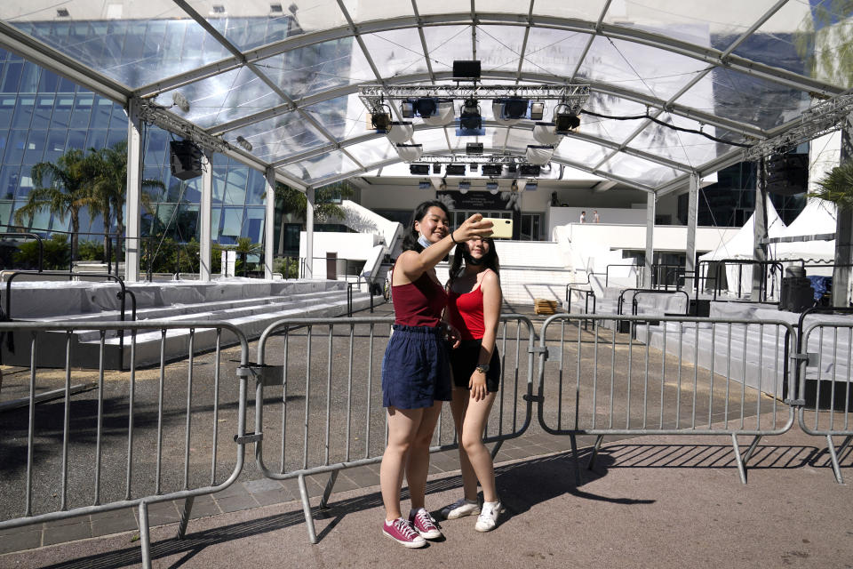 Members of the public take a selfie photograph in front of the entrance to the Palais des Festival prior to the 74th international film festival, Cannes, southern France, July 5, 2021. The Cannes film festival runs from July 6 - July 17, 2021. (AP Photo/ Brynn Anderson)