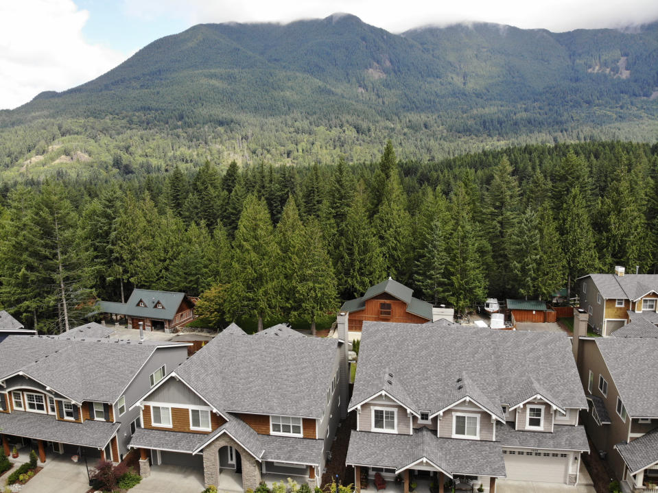 In this photo taken July 24, 2019, houses are backed up to a forest in the Cascade foothills of North Bend, Wash. Experts say global warming is changing the region’s seasons, bringing higher temperatures, lower humidity and longer stretches of drought. And that means wildfire risks in coming years will extend into areas that haven’t experienced major burns in residents’ lifetimes. (AP Photo/Elaine Thompson)