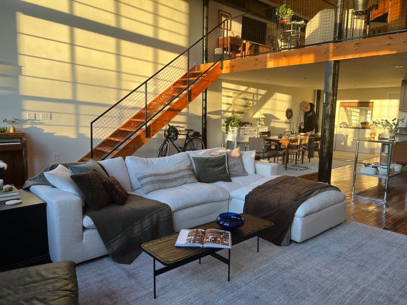 Neutral sectional topped with decorative pillows and throws in loft living room.