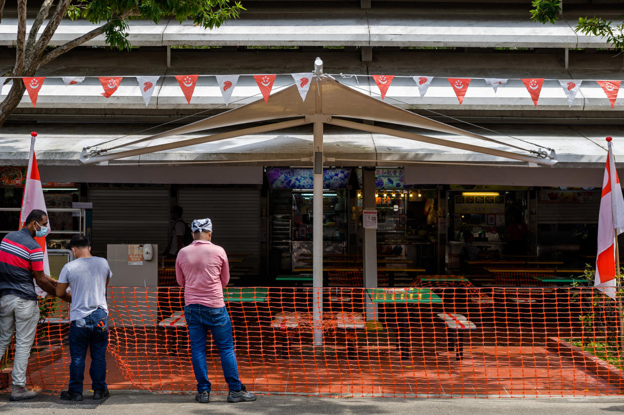 Workers cordon off the entry to a food centre in a housing estate in Singapore on Saturday, 24 July 2021. Access to the many food centres frequented by most of Singapore's local population will require visitors to use the national electronic tracking system to again entry. Dining in at eateries is no longer permitted by authorities as the country increased its lockdown measures to deal with rising cases of the Covid-19 virus that stemmed from its main fishing port and spread throughout wet markets in the country. (Photo by Joseph Nair/NurPhoto via Getty Images)