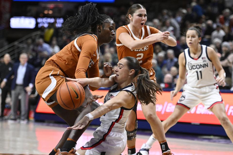 Connecticut's Nika Muhl, center, passes under pressure from Texas' Amina Muhammad, left, during the first half of an NCAA college basketball game, Monday, Nov. 14, 2022, in Storrs, Conn. (AP Photo/Jessica Hill)