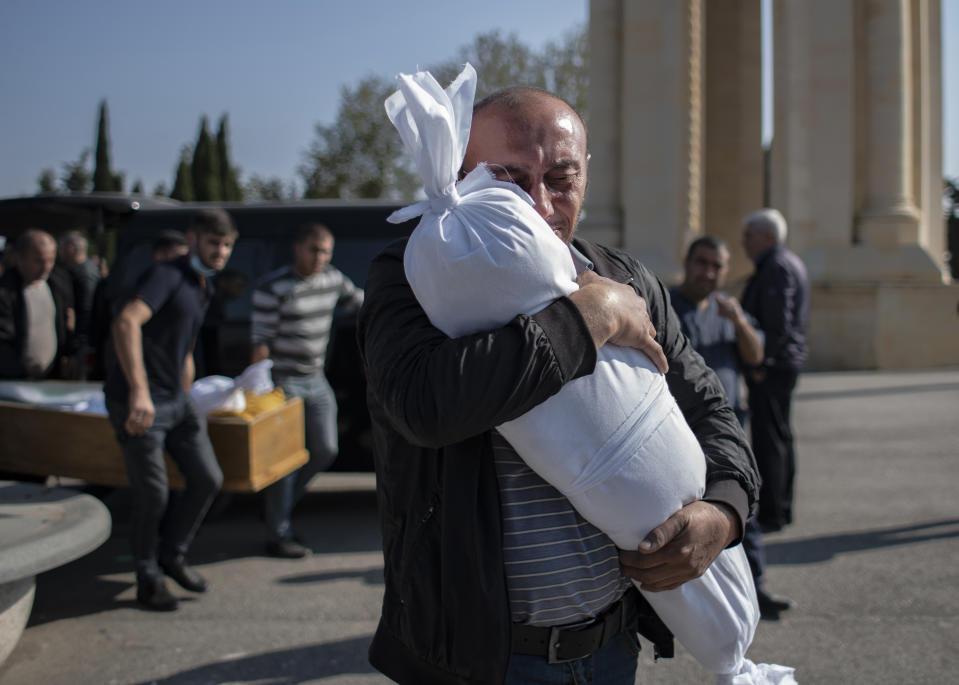 Timur Haligov, an Azerbaijani Turkish father embraces the body of his 10-month-old baby girl, Narin, who was killed by overnight shelling by Armenian forces. during a funeral ceremony, in Ganja, Azerbaijan, Saturday, Oct. 17, 2020. Azerbaijan has accused Armenia of striking its second-largest city with a ballistic missile that killed at least 13 civilians and wounded 50 others in a new escalation of their conflict over Nagorno-Karabakh. (Can Erok/DHA via AP)
