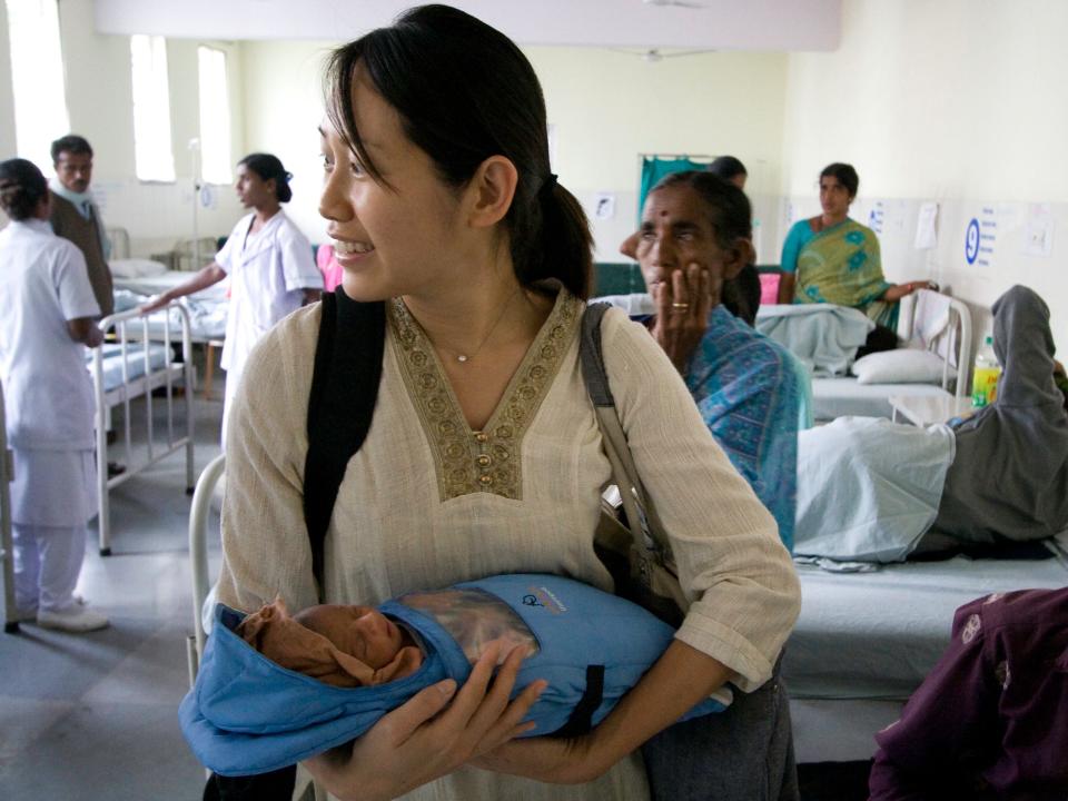 Jane Chen, the co-founder of Embrace Global, holds a baby using a low-cost incubator