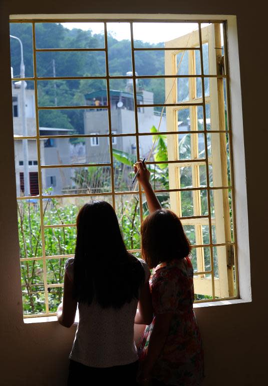 H'mong ethnic teenager May Na (L) (whose name has been changed to protect her identity) and a roommate look out from a window at a government-run centre for trafficked women in the northern city of Lao Cai, May 9, 2014