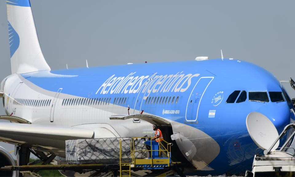 Workers unload the first shipment of Russia's Sputnik V COVID-19 vaccine from an airplane at the international airport in Buenos Aires, Argentina, Thursday, Dec. 24, 2020. (AP Photo/Gustavo Garello)