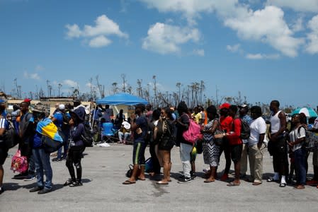 People wait in line to get in a airplane during an evacuation operation after Hurricane Dorian hit the Abaco Islands in Treasure Cay