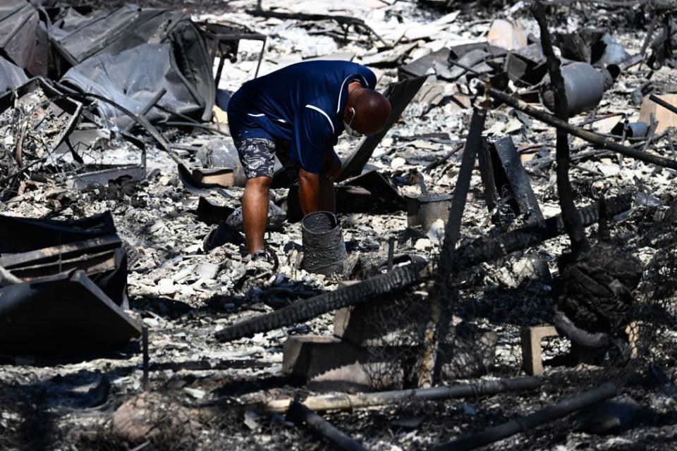 Hano Ganer looks through the ashes of his family's home on Malolo Place in Lahaina, western Maui, Hawaii.