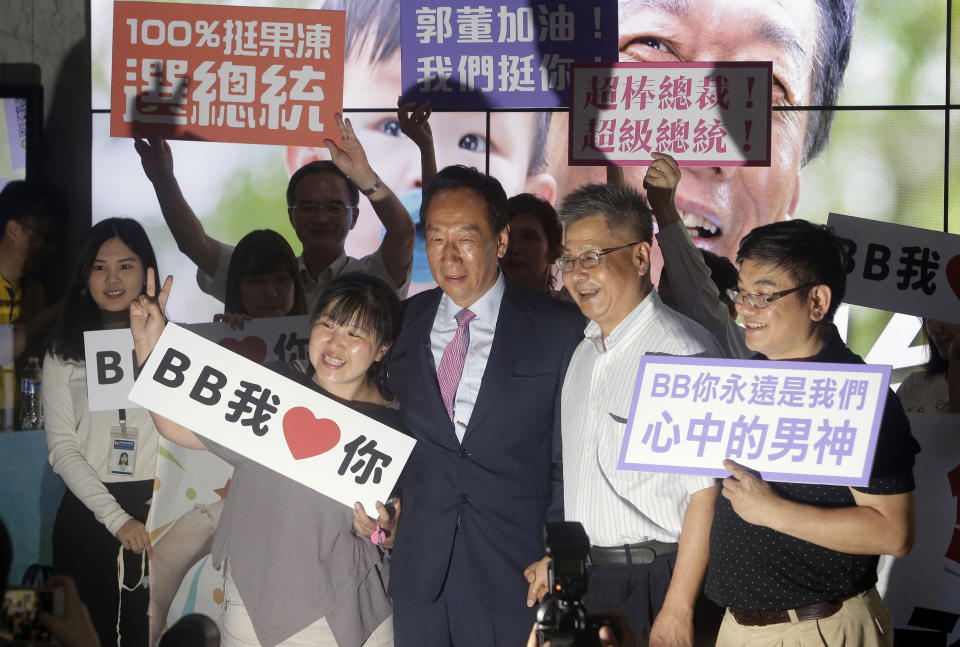 FILE - In this June 21, 2019, file photo, Terry Gou, center, chairman of Foxconn, the world's largest contract assembler of consumer electronics, poses with supporters for a photo after the company's annual shareholders meeting in New Taipei City, Taiwan. Gou has given up on making a bid for Taiwan's presidency. Gou announced his decision in a statement late Monday, Sept. 16, 2019, one day before a deadline to register for the race. (AP Photo/Chiang Ying-ying, File)