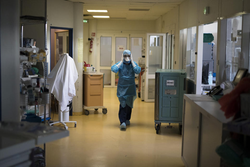 A healthcare worker wearing protective equipment walks through the intensive care unit at the Joseph Imbert Hospital Center in Arles, southern France, Wednesday, Oct. 28, 2020. Many French doctors are urging a new nationwide lockdown, noting that 58% of the country's intensive care units are now occupied by COVID patients and medical staff are under increasing strain. (AP Photo/Daniel Cole)