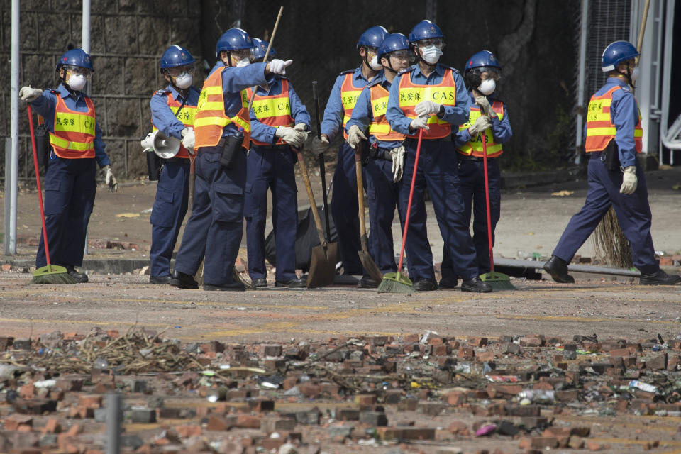 Workers start to clean up the road outside the Hong Kong Polytechnic University in Hong Kong on Wednesday, Nov. 20, 2019. Hong Kong schools have reopened after a six-day shutdown but students were facing transit disruptions as the last protesters remained holed up on a university campus. (AP Photo/Ng Han Guan)